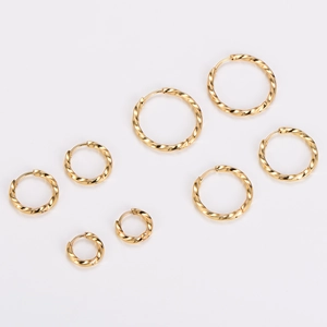 Detailed view of four pairs of golden twisted hoop earrings in various sizes on white background