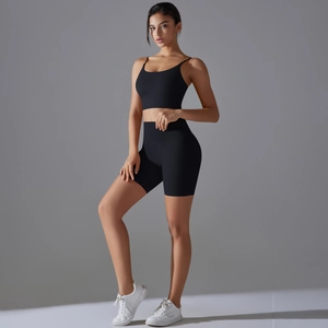 Vista laterale di una donna in completo yoga nero a vita alta con reggiseno e pantaloncini
