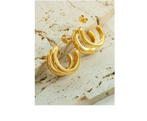 Detail of 18K gold plated triple hoop earrings resting on minimalist travertine stone