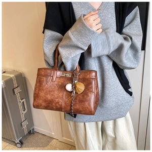 Sac Kelly vintage marron avec doubles poignées, fermoir rotatif et breloques de sac