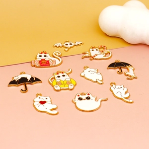 Detailed view of white enamel gold-plated cat and ghost charms for DIY jewelry making