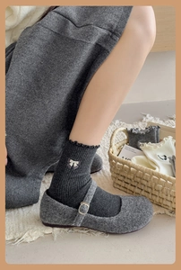 Detail of grey mid-calf socks with white bow paired with wool Mary Jane shoes
