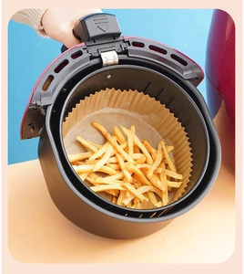 Disposable round air fryer paper liner with french fries in a basket for baking