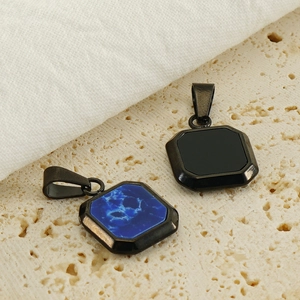 Detail of square pendants with blue textured stone and black smooth stone on stone surface