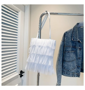 Close-up of a white layered lace fringe shoulder bag with ruffled fabric texture