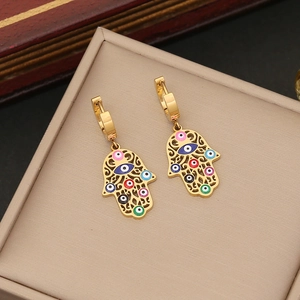 Golden Hamsa hand earrings with colorful evil eye charms on a beige jewelry display box