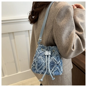 Denim quilted bucket bag with frayed edges and leather drawstring shoulder strap