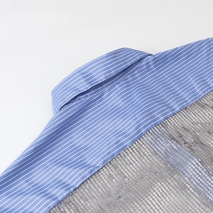 Détail du tissu à rayures bleues et blanches avec paillettes argentées sur la chemise