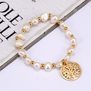 Elegant baroque pearl bracelet with gold tree of life pendant on a magazine background