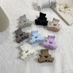 Flat lay of eight colorful bear hair claws with matte finish on textured fabric
