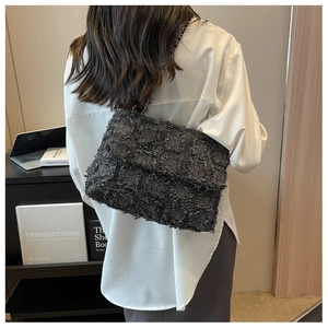 Detail of dark gray textured tote bag with chain strap shown in a modern office setting
