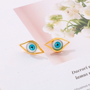 Close-up of bohemian gold stud earrings featuring a blue evil eye design in resin