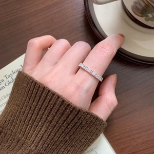 Detail of a 925 sterling silver zircon ring on model's hand with cozy wooden background