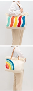 Dettaglio della borsa tote in tela con manici in ecopelle marrone e nappe colorate trapuntate