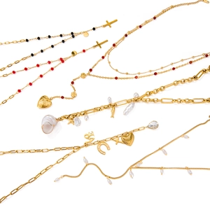 Golden multi-layer stainless steel necklaces with cross, heart, and pearl charms on white background