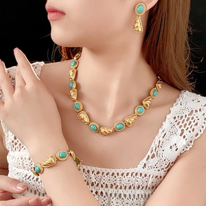 Gros plan d'un collier vintage doré et boucles d'oreilles turquoise sur un mannequin