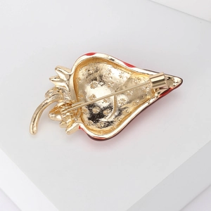 Back view of gold strawberry enamel brooch with pin clasp on white display stand