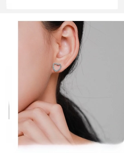 Gros plan d'une boucle d'oreille cœur minimaliste avec pavé de pierres bleues sur l'oreille
