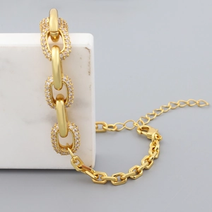 Detail of hip hop gold chain bracelet with pavé rhinestones on white marble blocks
