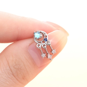 Boucle d'oreille attrape-rêves en argent avec zircon bleu et pompons entre doigts