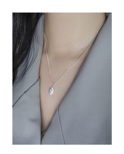 Detailed view of an S925 sterling silver sunburst opal pendant on a model's collarbone
