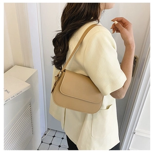 Khaki minimalist crossbody bag shown with side view on model in bright home setting