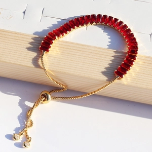 Detail of red rectangular crystal bracelet with golden slider chain and adjustable clasp