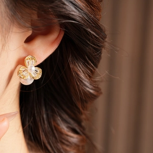 Nahaufnahme eleganter Blumenohrringe in Gold mit weißen Perlen und Zirkonia am Modell