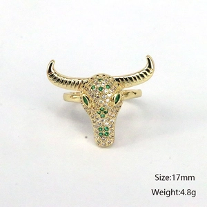 Détail d'une bague tête de bœuf dorée avec zircons verts, taille 17mm et poids 4,8g