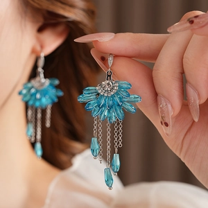 Détail macro de boucles d'oreilles en éventail avec cristaux bleus et pompons en argent