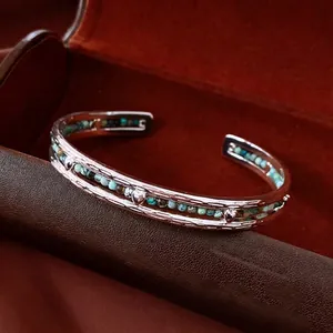 Silver wavy open bangle with heart accent and turquoise beads on leather display