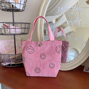 Detailed close-up of pink corduroy tote bag with smiley face print and metal snap button