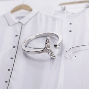 Elegant silver fishtail open ring with shimmering zircon stones on a white artistic base