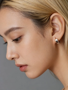 Close-up of minimalist silver hoop earrings on a model showing size and metallic luster