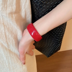 Détail d'un bracelet jonc en acrylique rouge vif au poignet avec fini brillant