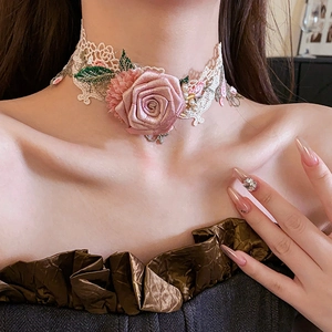 Close-up of lace choker with pink fabric rose, green leaves and delicate pearl beads