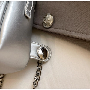 Close-up of silver leather crossbody bag with metallic chain and detailed stitching
