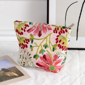Detail of floral jacquard fabric texture and golden metal zipper on a trapezoid makeup bag