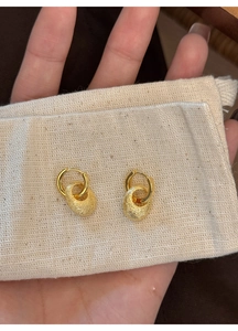 Nahaufnahme goldener ovaler Ohrringe mit strukturierter Oberfläche und Glanz