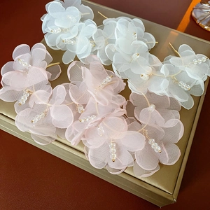 Détail de boucles d'oreilles fleurs avec pétales en tulle blanc et rose et crochets dorés