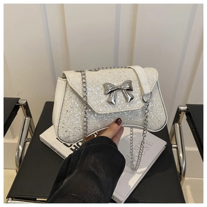 Close-up of white sequin handbag with silver metal bow and chain strap detail