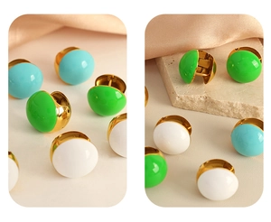 Detailed macro view of retro gold-plated earrings in green, blue, and white colors