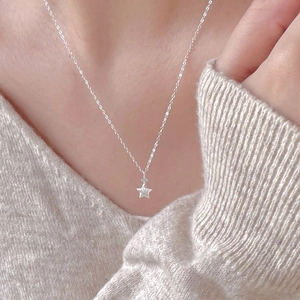 Minimalist S925 sterling silver star necklace with zircon on a model in knitwear