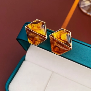 Macro shot of vintage hexagonal amber resin earrings in gold setting on velvet