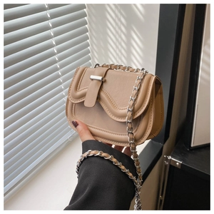 Detail of tan synthetic leather texture and silver chain strap on a saddle bag