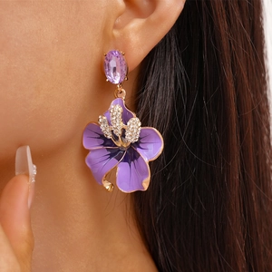 Dettaglio dell'orecchino a fiore viola con petali smaltati e cristallo sul modello
