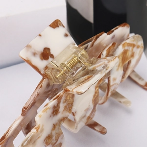 Close-up of marble pattern acetate hair claw clip showing brown veins and spring detail
