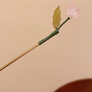 Close-up of pink tulip hair pin with green thread detail and golden metallic finish
