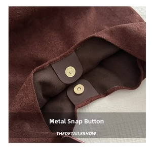 Detail of burgundy suede shoulder bag showing the dual golden magnetic snap closures