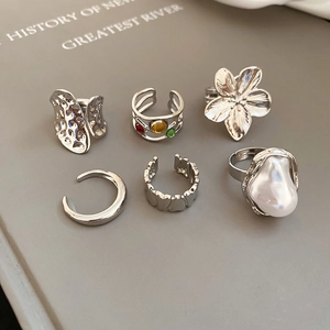 Close-up of six-piece silver ring set with floral textures and baroque pearls on book